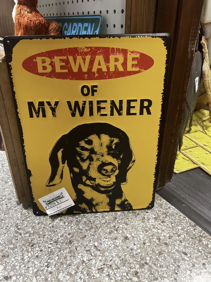 Humorous sign with &quot;BEWARE OF MY WIENER&quot; text and a dachshund illustration, meant as a joke for dog owners