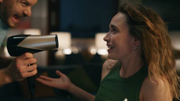 Man seeking attention from woman by putting a blow dryer in her face