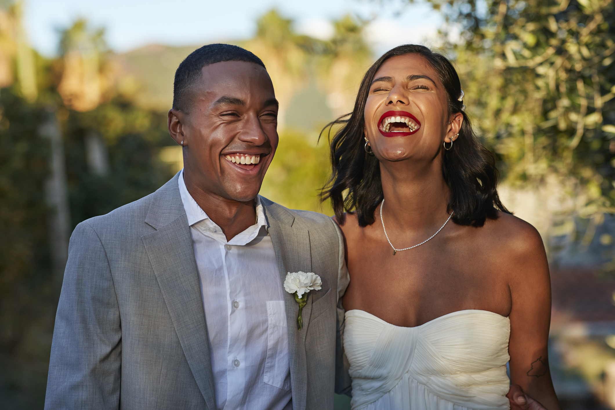 Two people in wedding attire smiling joyfully, likely a couple