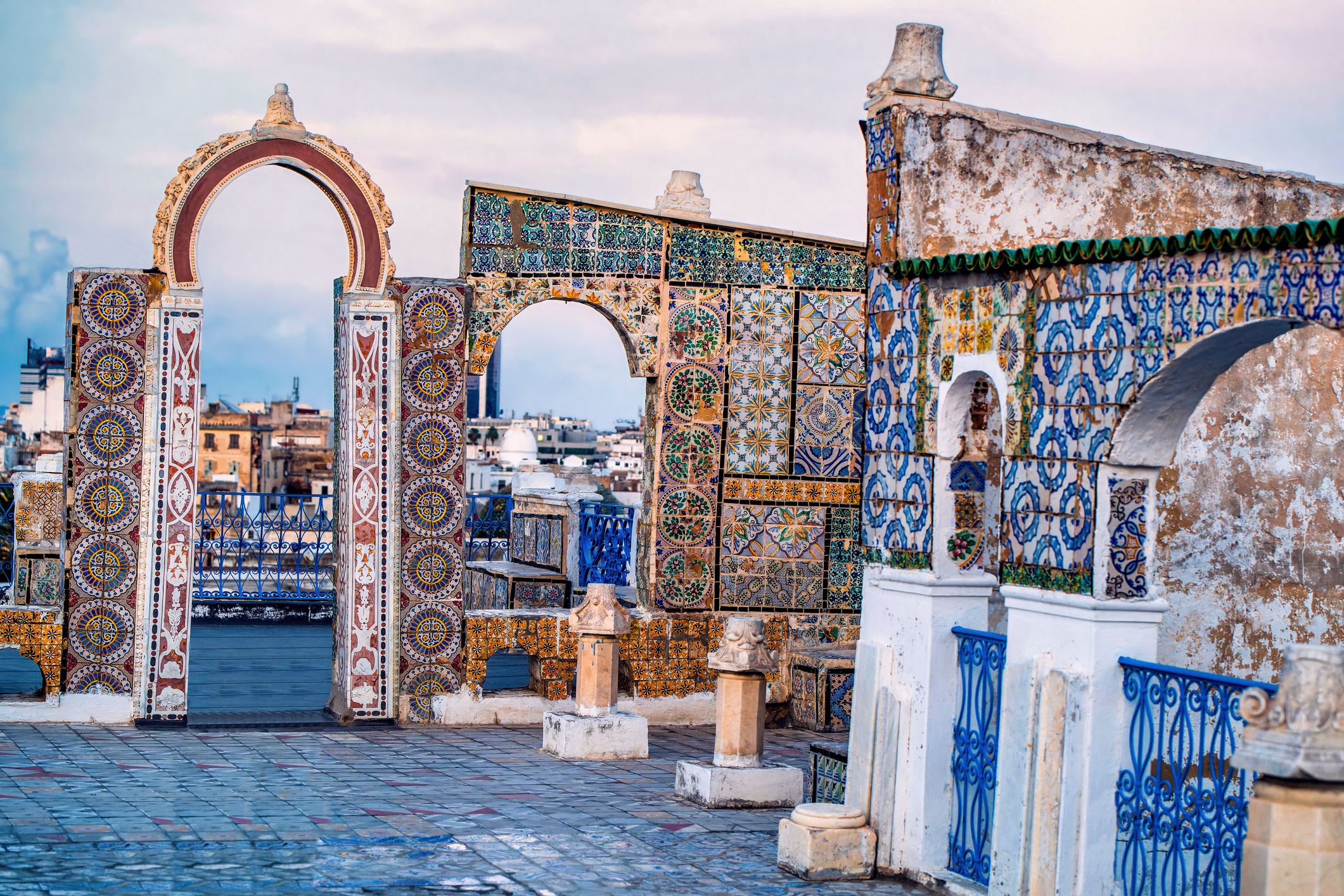 Rooftop view with ornate mosaic archways overlooking a cityscape at dusk