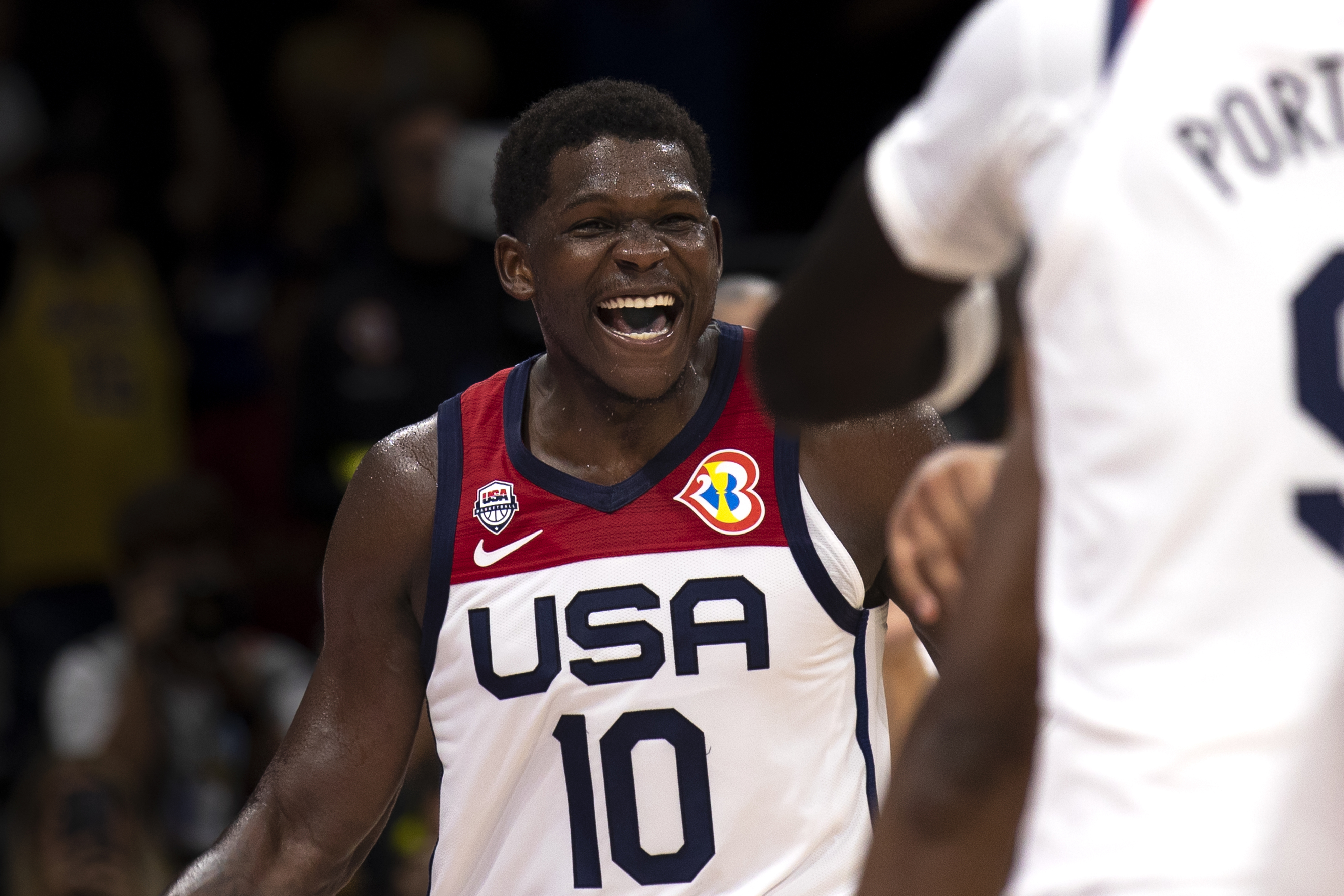 Athlete in USA jersey with number 10 laughs on the basketball court next to a teammate