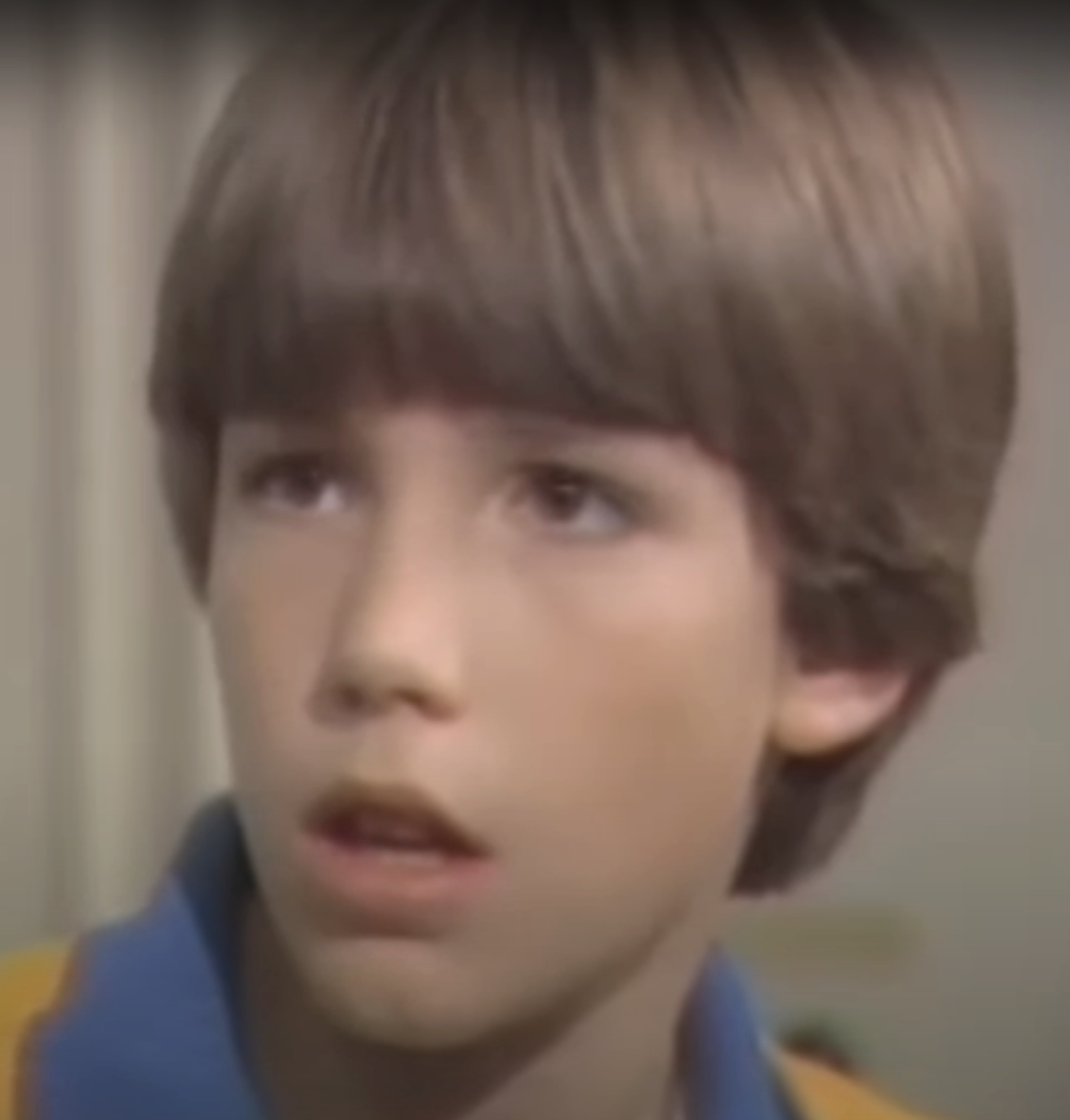 Close-up of a young Ben portraying emotion, wearing a striped shirt