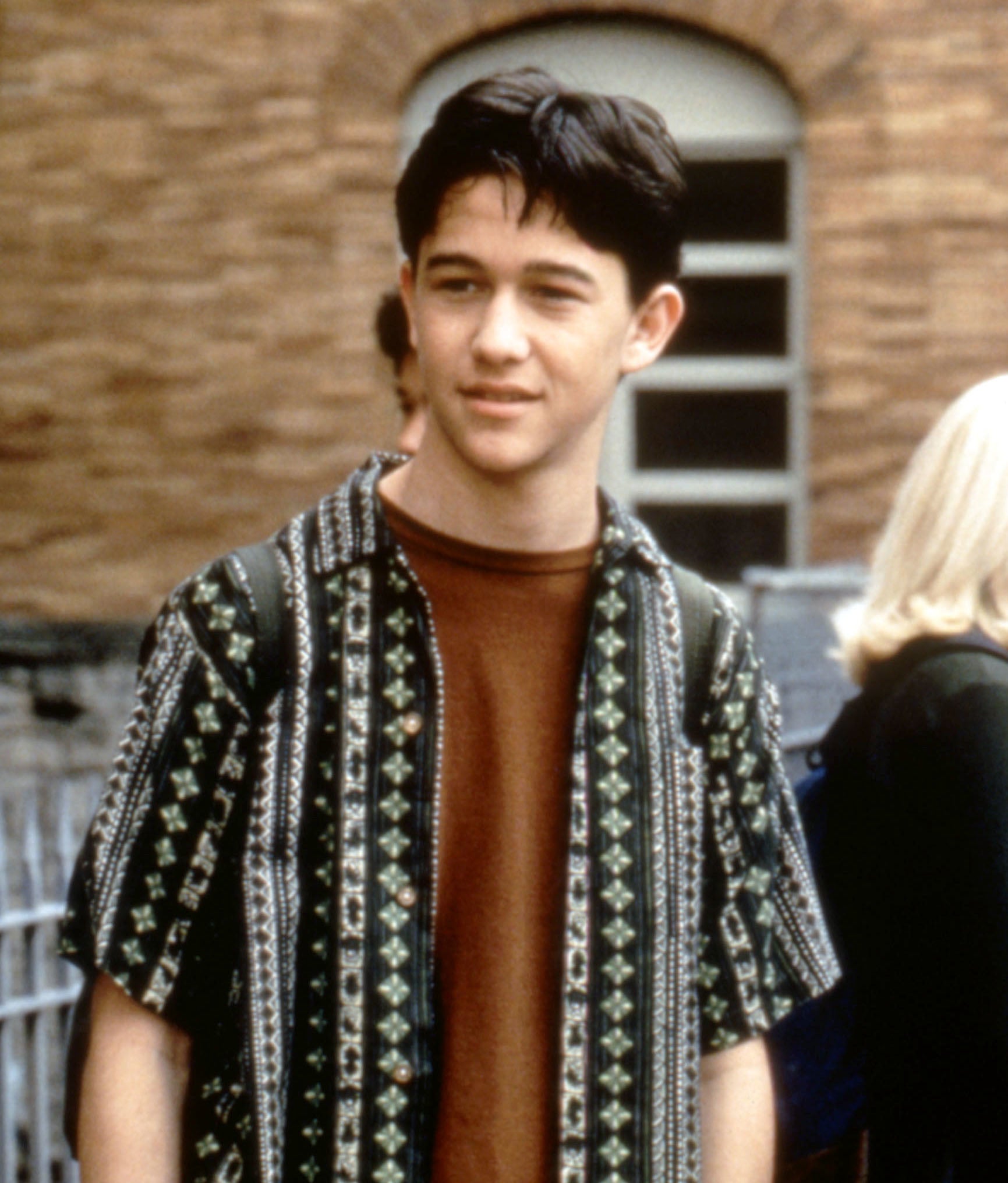 in a scene, Gordon stands in a patterned shirt open over a t-shirt