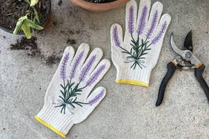 A pair of gardening gloves with floral design next to pruning shears on concrete