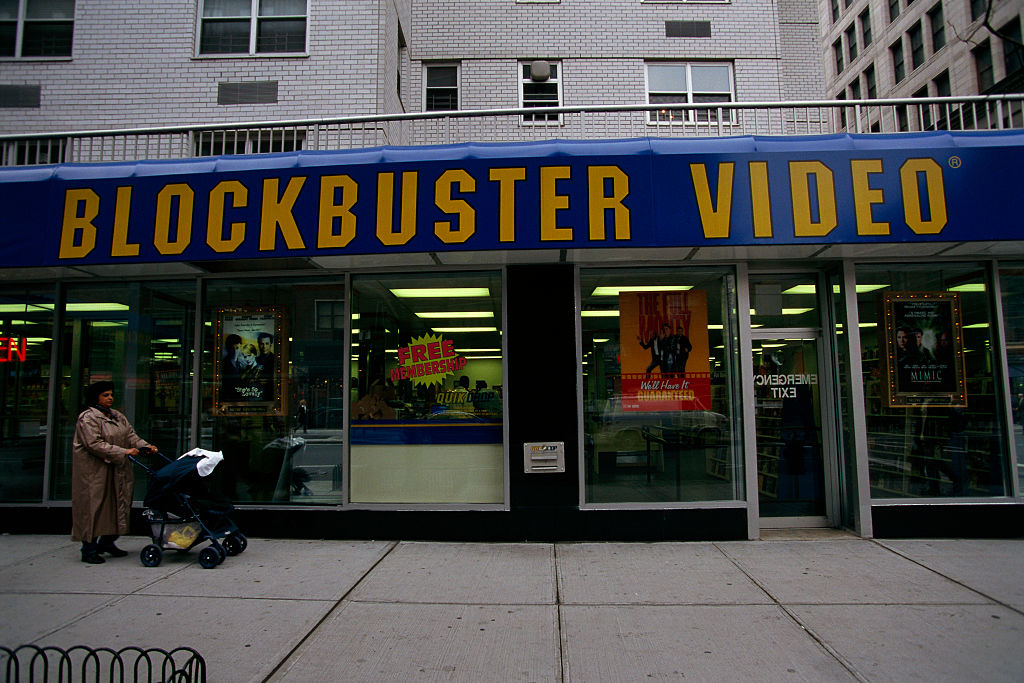 Exterior of a Blockbuster Video store with a person pushing a stroller passing by