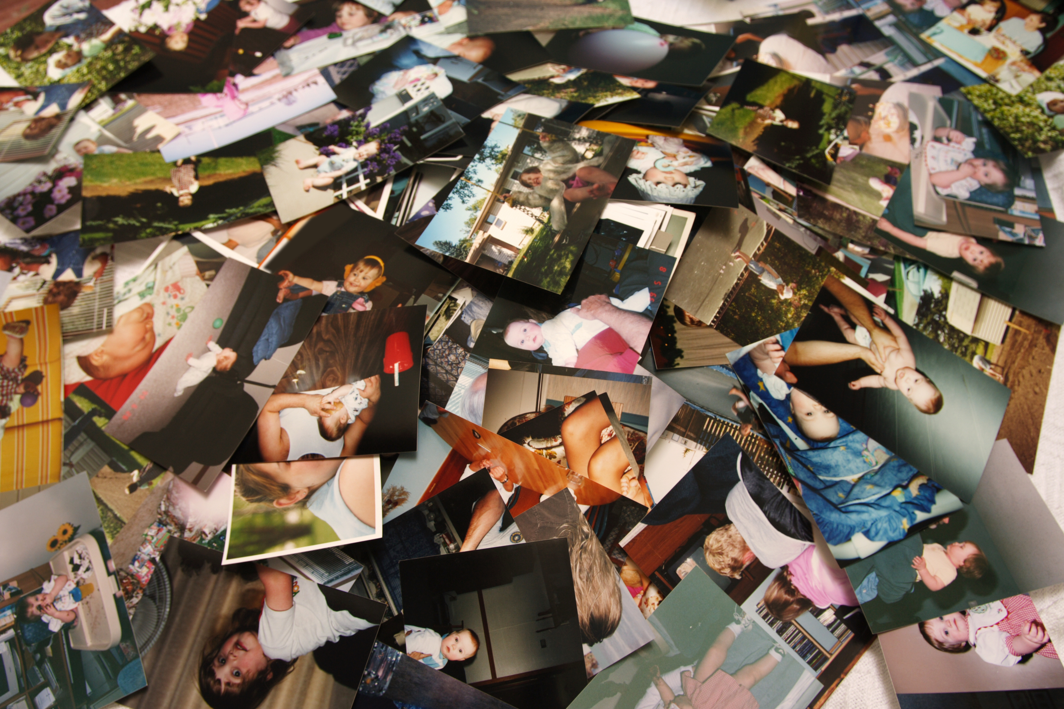 A scattered collection of assorted family photographs spread out on a surface