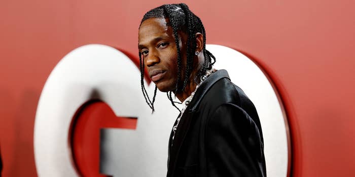 Travis Scott posing in a black jacket with braided hair at a GQ event