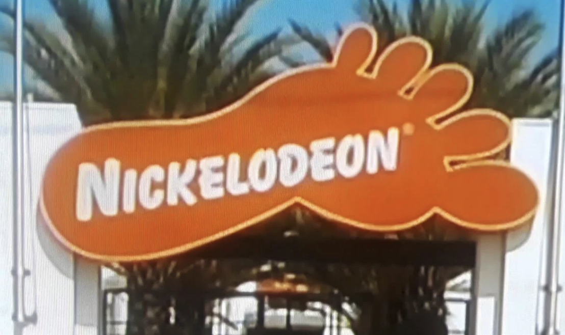 Nickelodeon logo with iconic orange splat shape and white text in front of palm trees