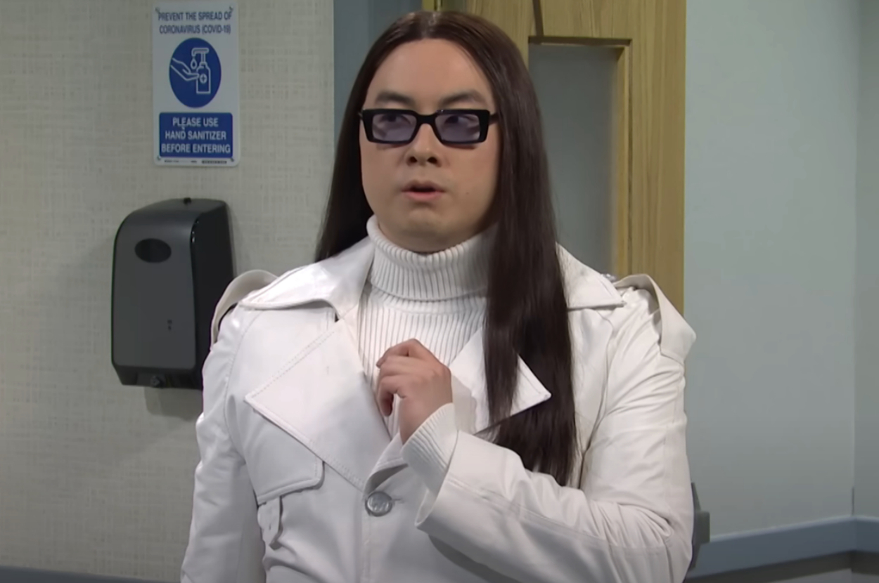 Bowen Yang looking off to the side while wearing a chic turtleneck and coat in an SNL sketch