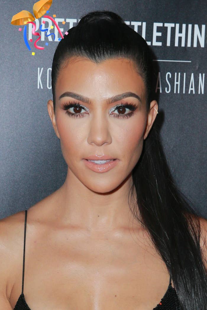 Kourtney Kardashian poses head-on at an event, wearing subtle makeup and a sleek hairstyle