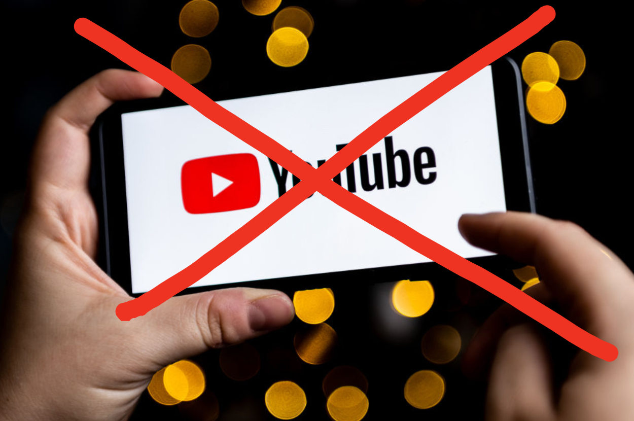 Hand holding a smartphone with YouTube logo crossed out, indicating prohibition or censorship