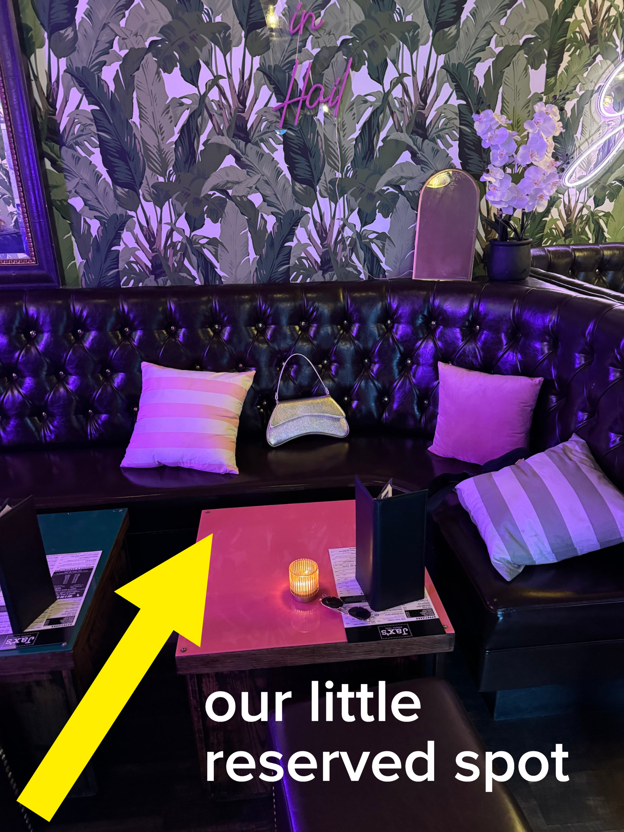 Restaurant booth with pillows, a menu, and a lit candle on the table