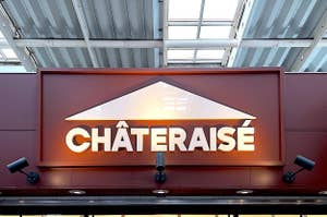 Storefront sign for "CHATERAISE" with illuminated letters, flanked by two spotlights