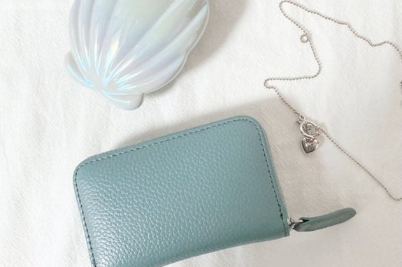 青い財布と白い背景に花の形の装飾とネックレスが置いてある。