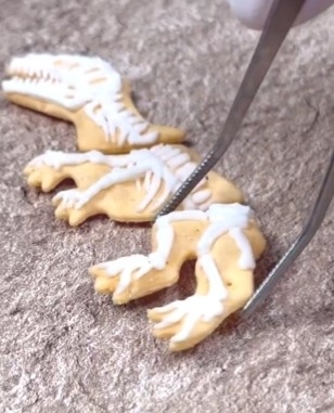 アイシングで装飾されている恐竜型のクッキーに細工をしている様子。