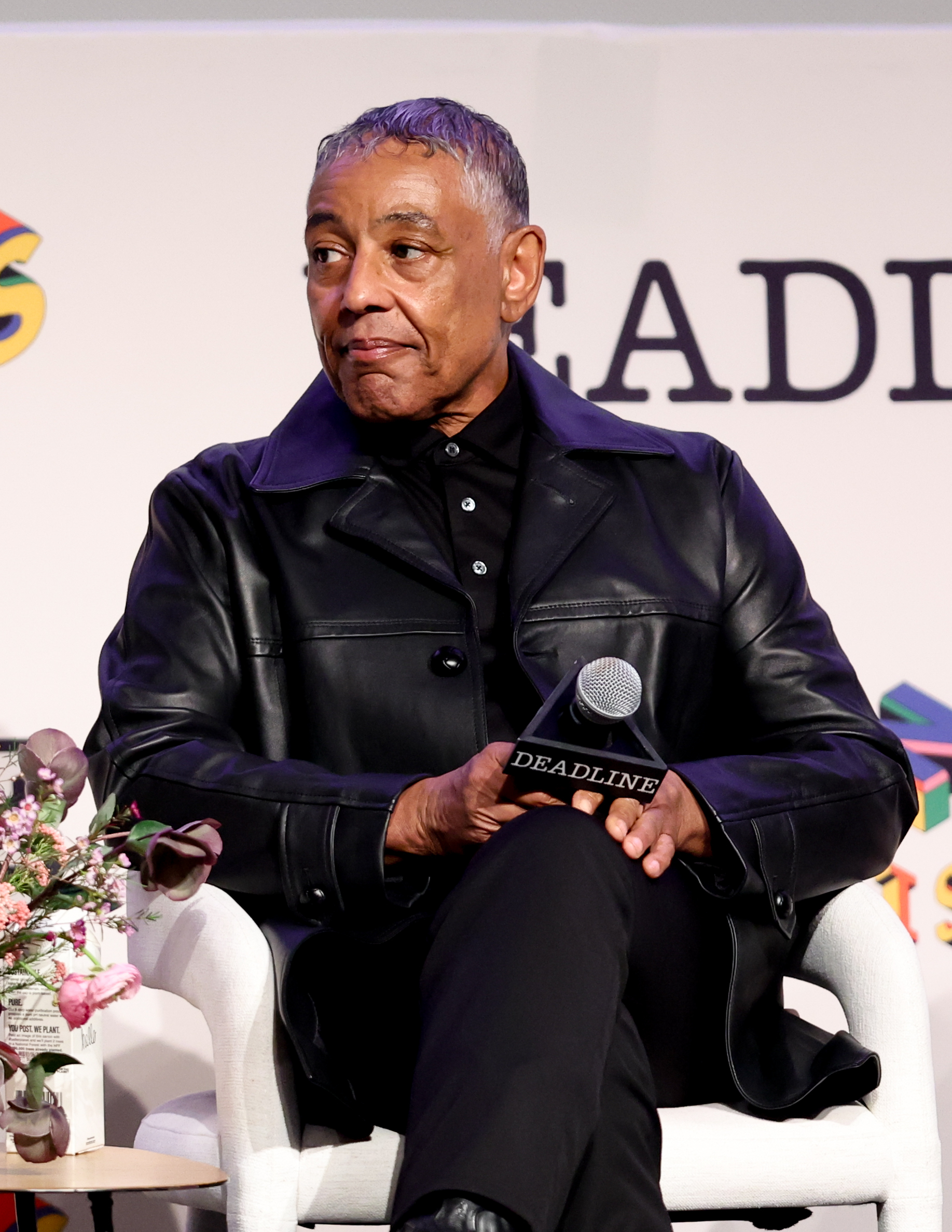 Giancarlo Esposito sitting engaged in a discussion at an event