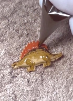 靴のヒールに挟まれた恐竜の形をしたキーホルダー