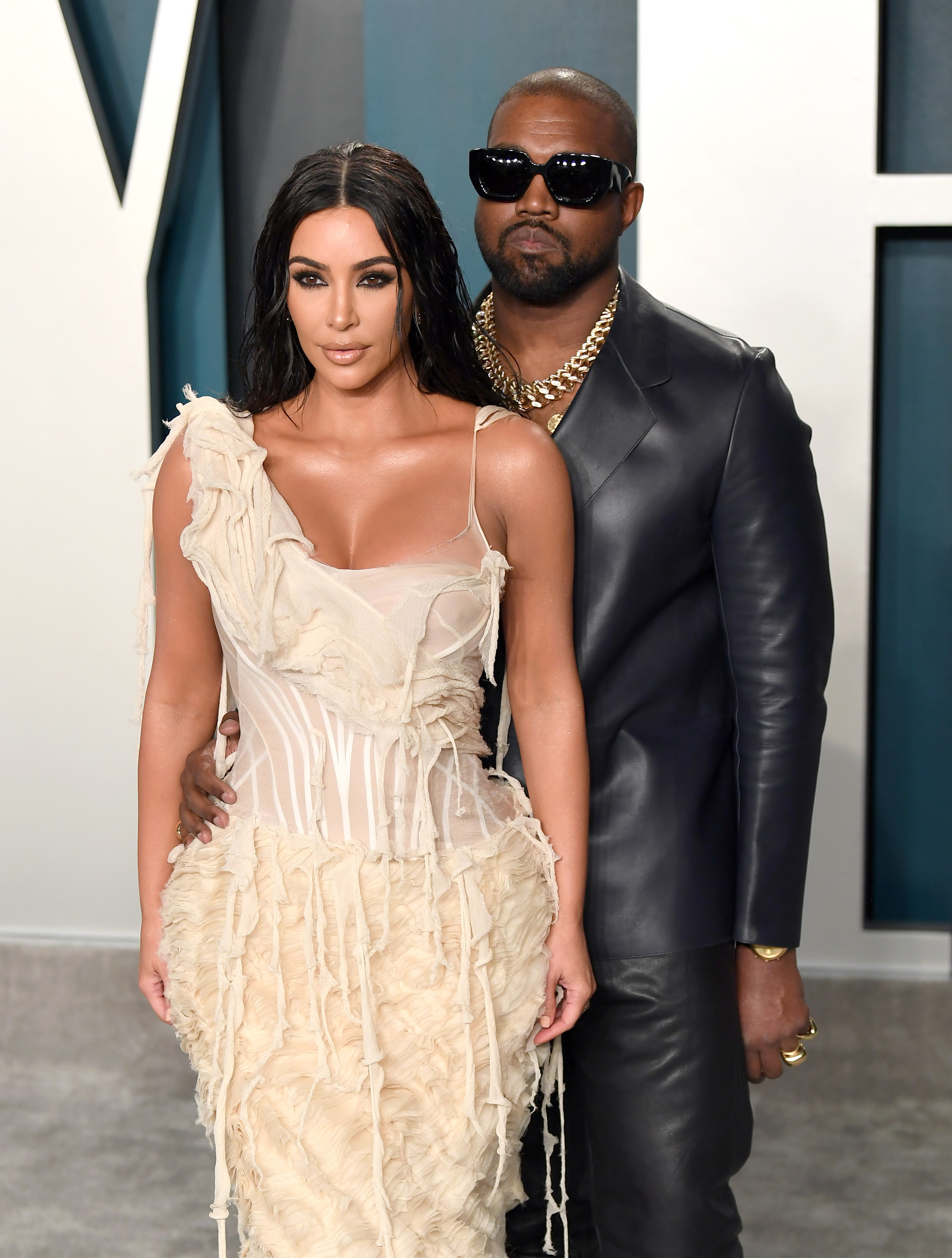 Kim Kardashian in a ruffled dress and Kanye West in a leather jacket posing on the red carpet