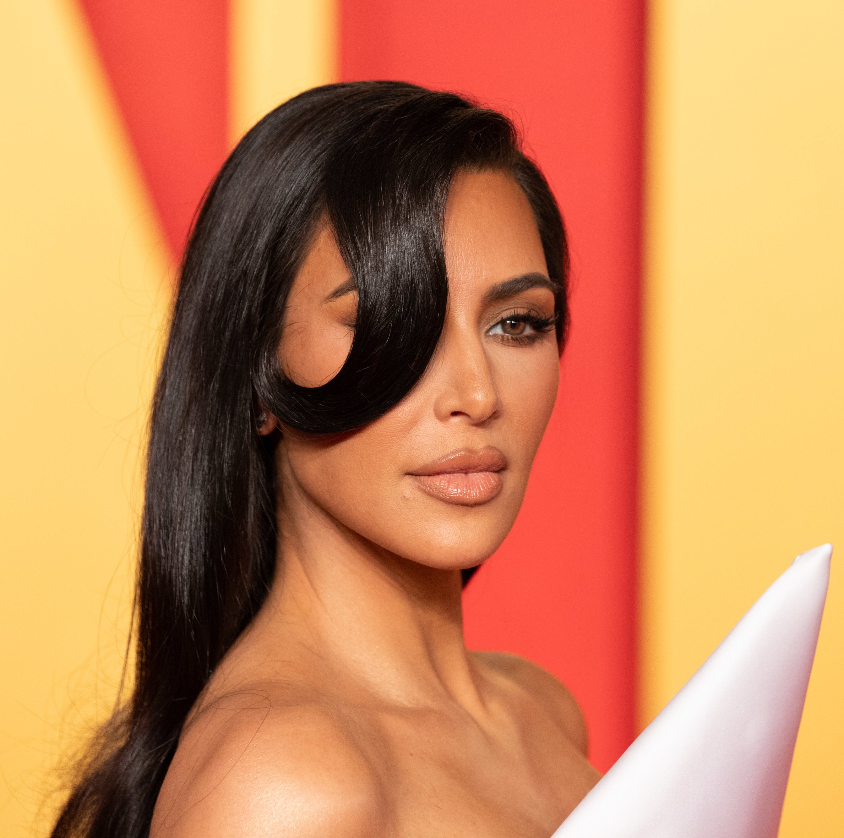 A closeup of Kim Kardashian in a structured, strapless at an event