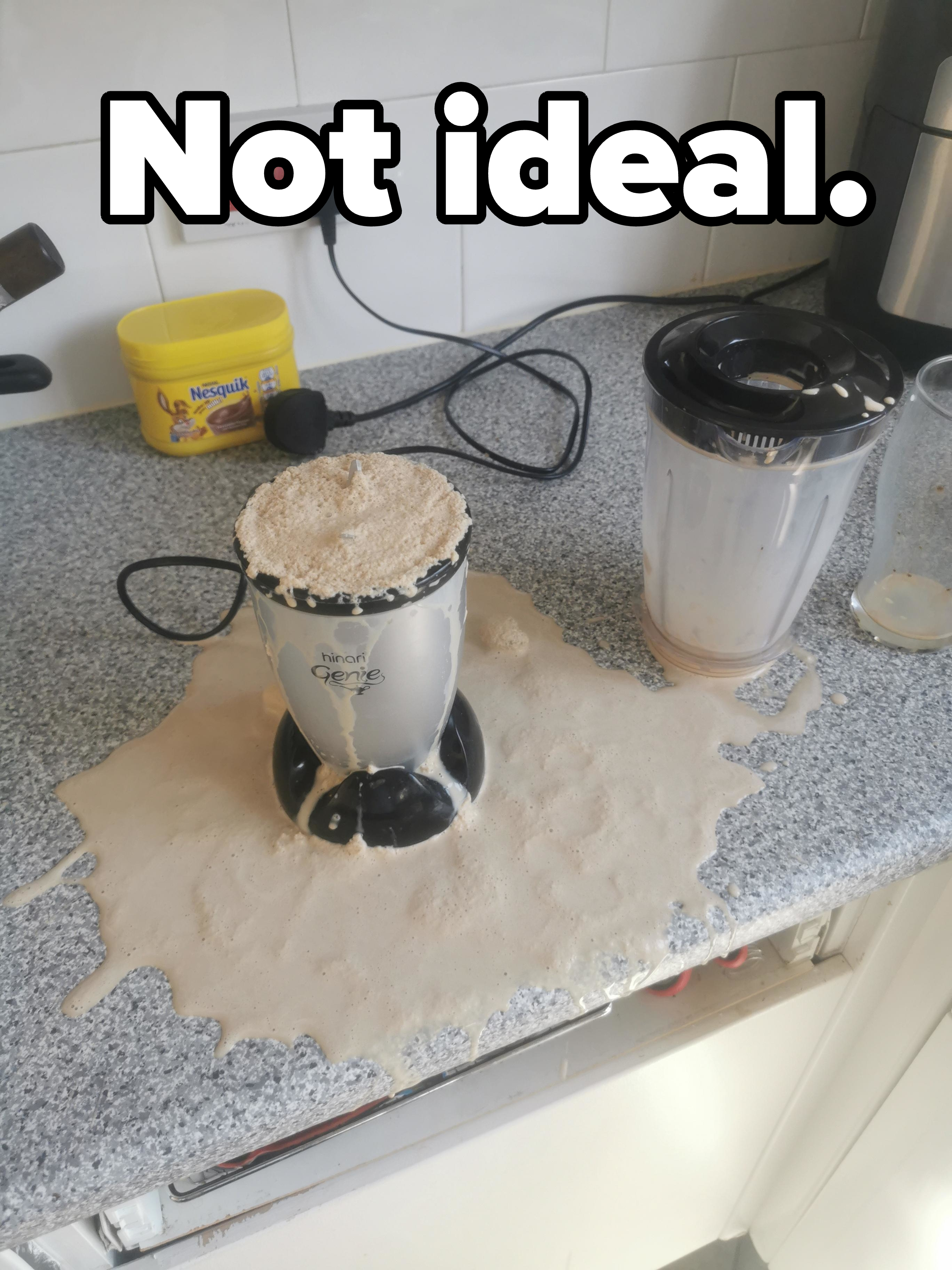Blender on a kitchen counter with an overflowed smoothie mess, next to an unplugged blender jug