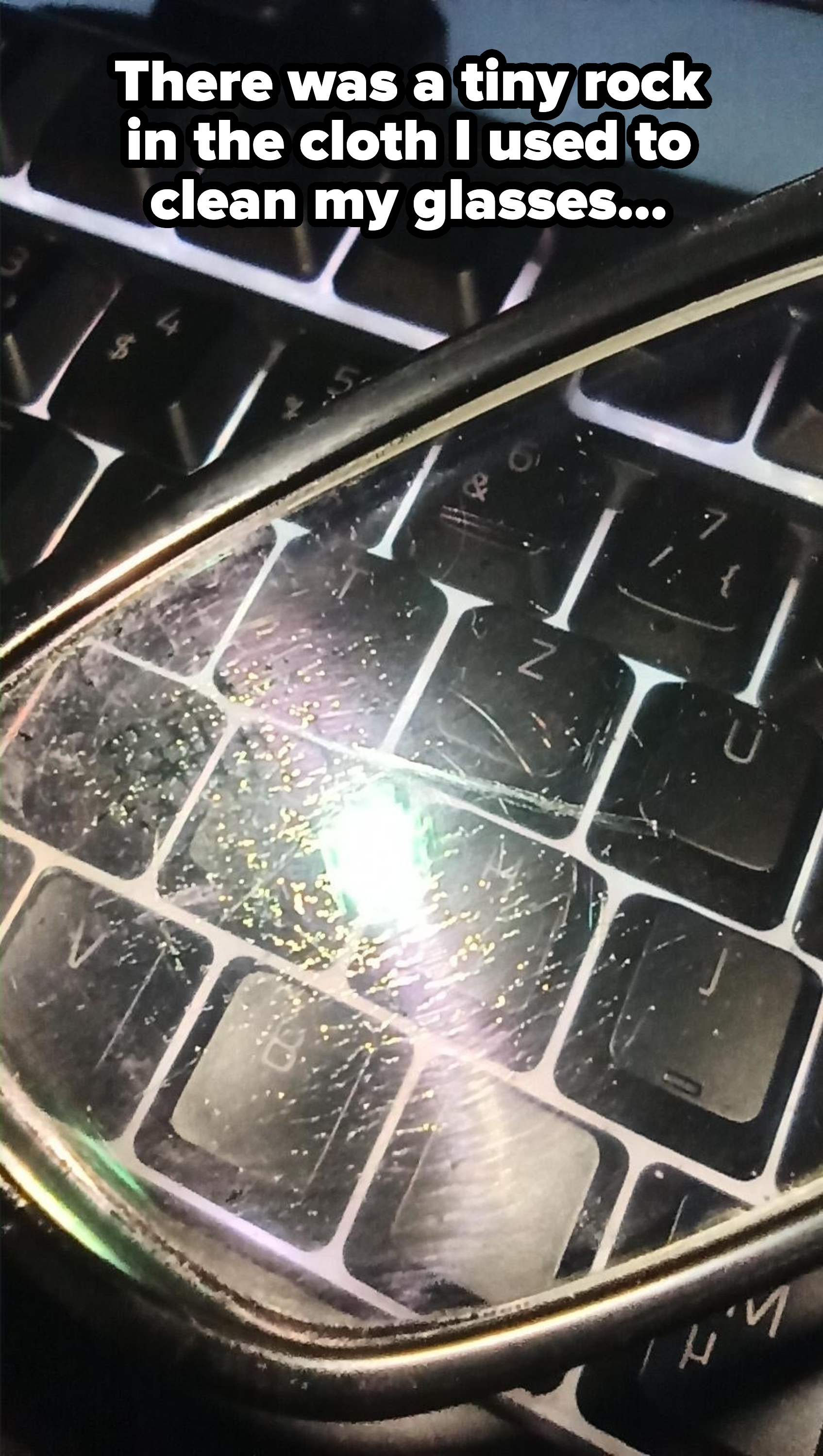 Close-up of dirty glasses lying on a laptop keyboard, reflecting light