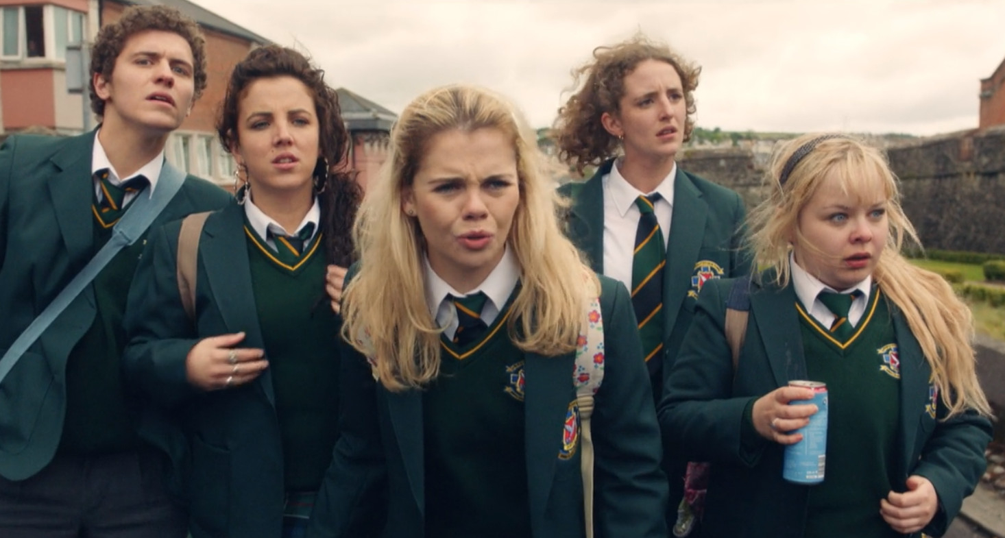 Four characters from the TV show Derry Girls in school uniforms walking with shocked expressions