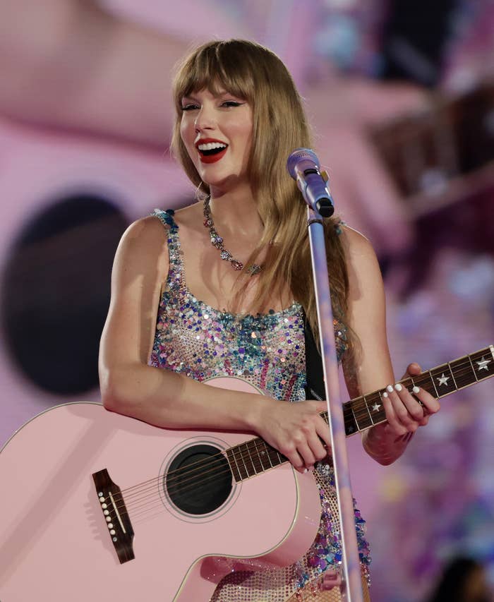 Taylor Swift performing with a glittery top and a guitar