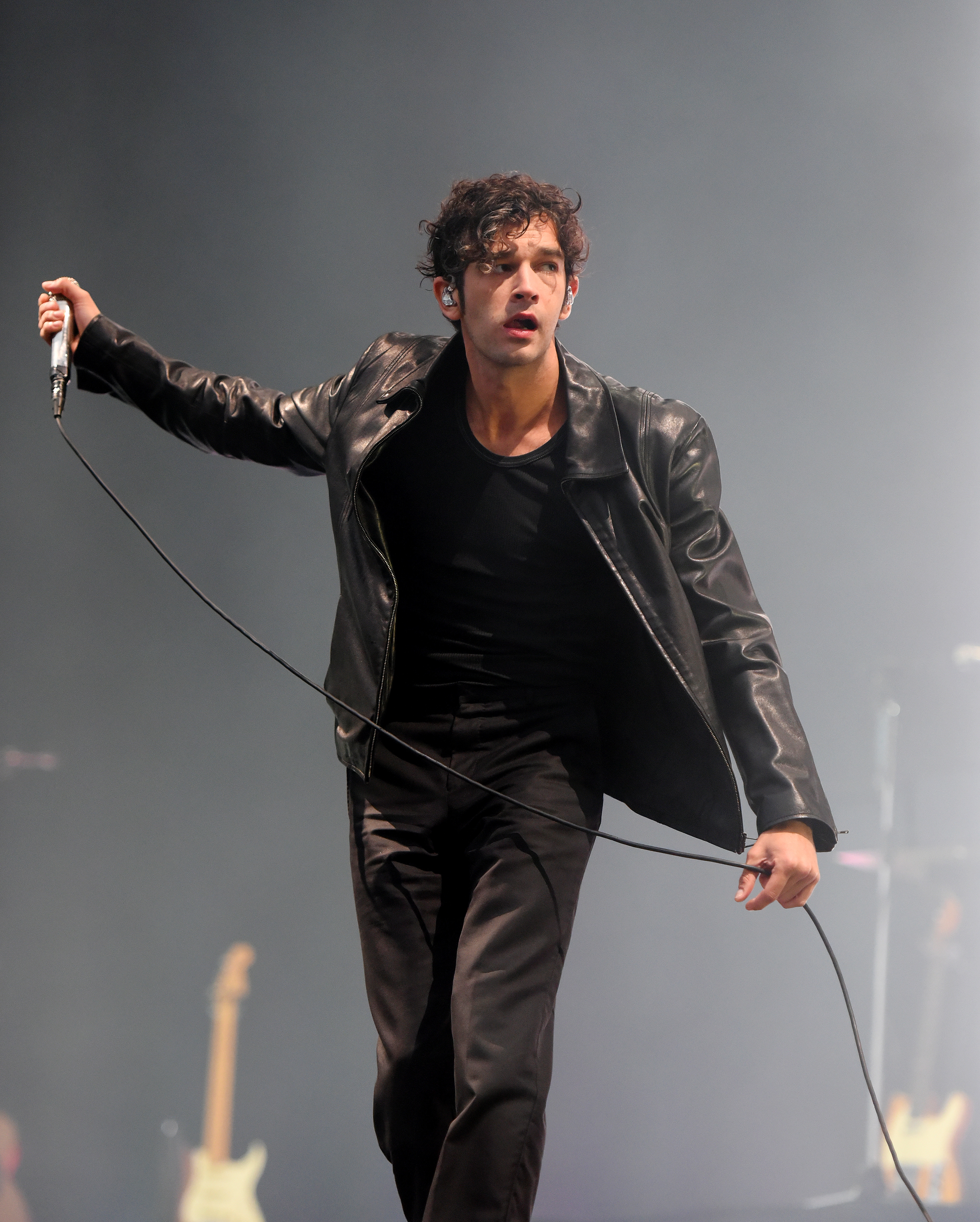 Matt Healy in a leather jacket  performing on stage