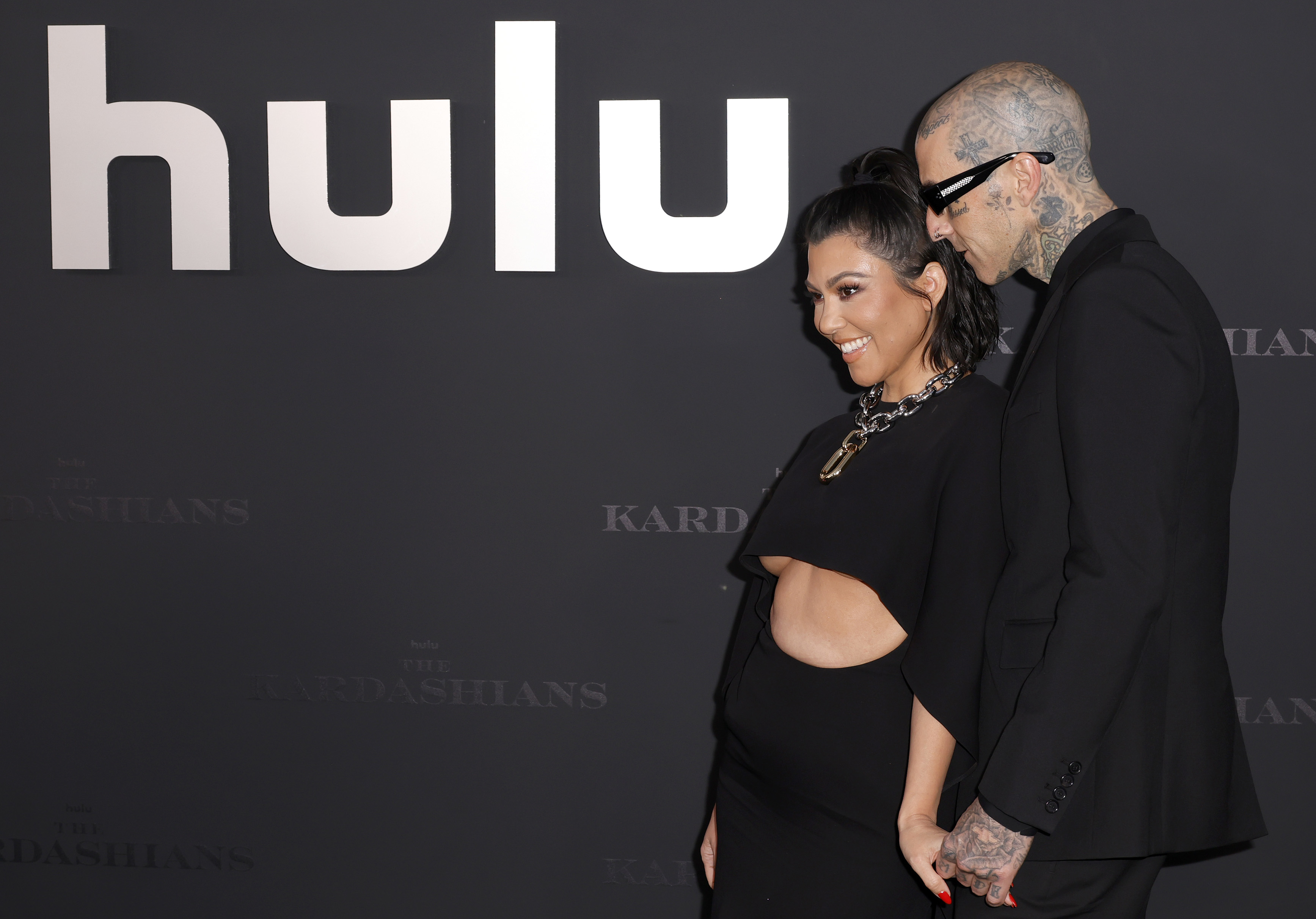Kourtney and Travis hold hands as they stand on the red carpet