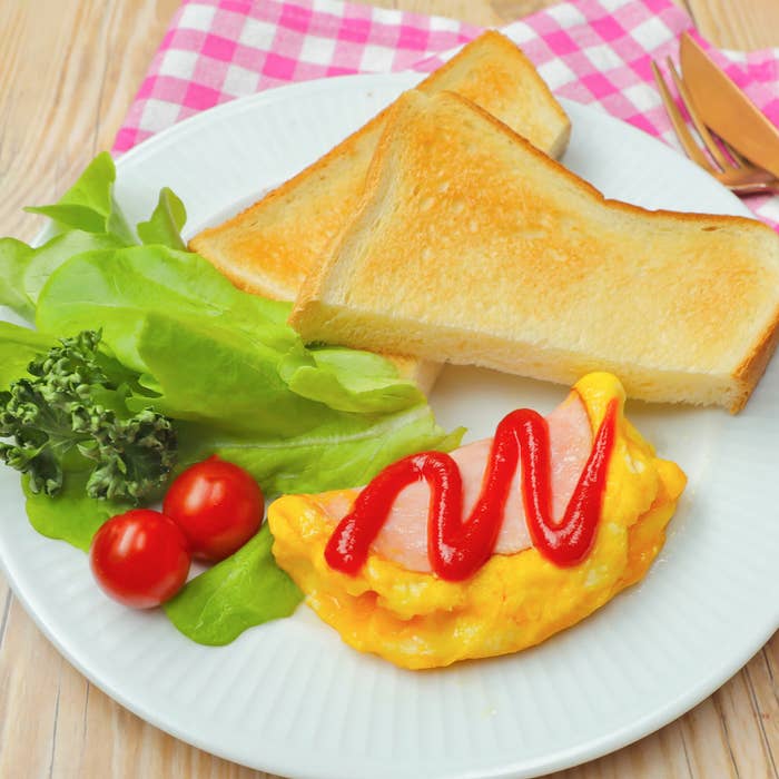 ハムエッグにケチャップがかかっている皿とトーストが写っています。サイドにレタスとトマトが添えられています。