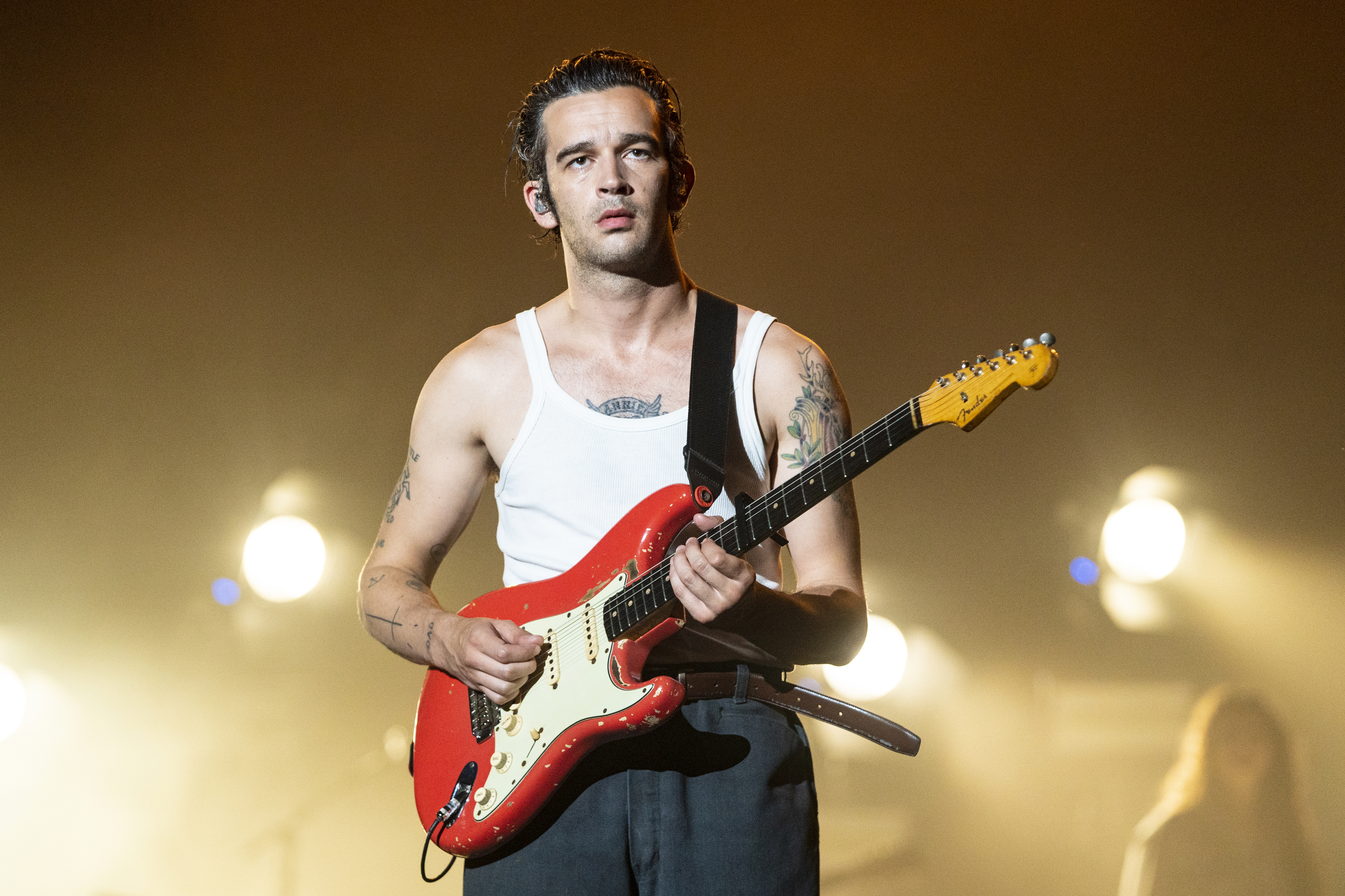 Matty Healy playing the guitar on stage