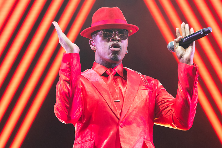 Performer in red suit and hat singing into a microphone onstage