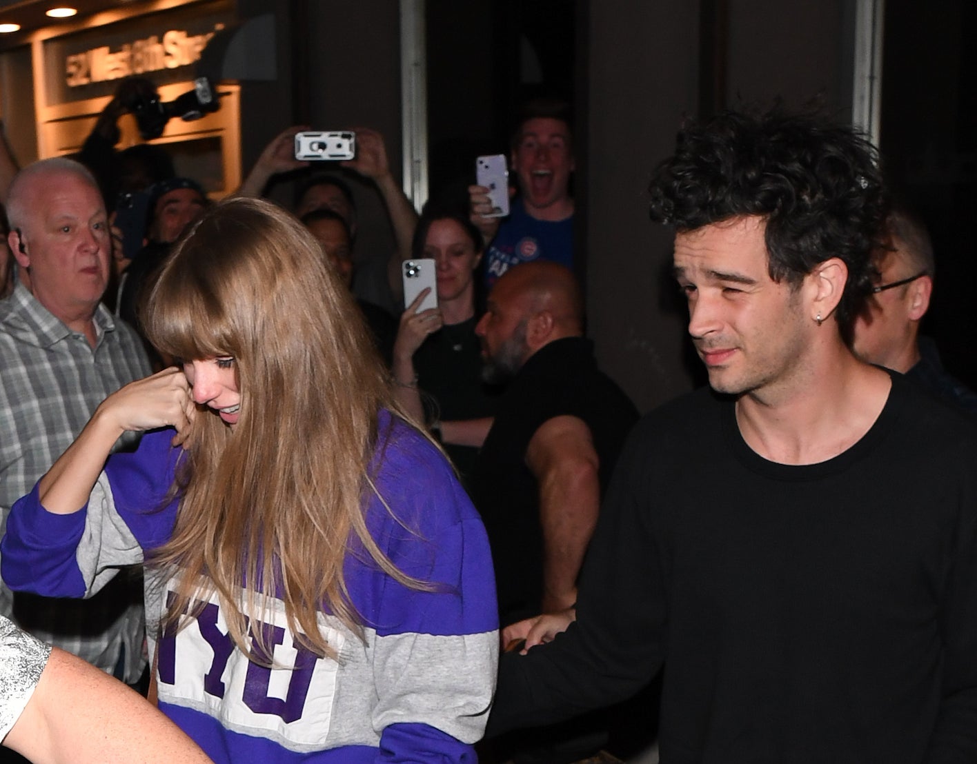 Taylor Swift in a casual outfit walks with Matty, surrounded by fans and security