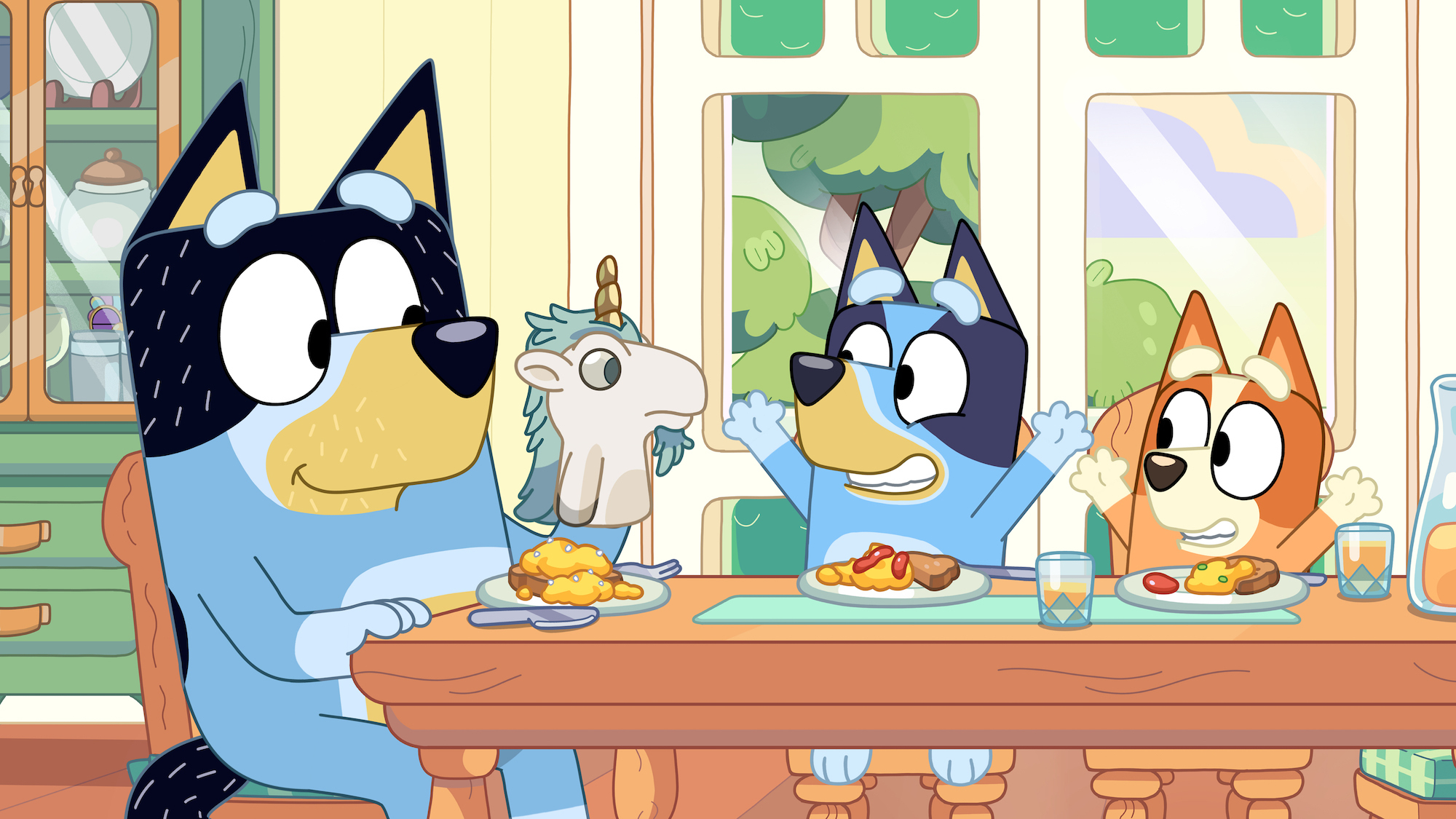 Animated characters Bluey, Bingo, and their parents eating at a table