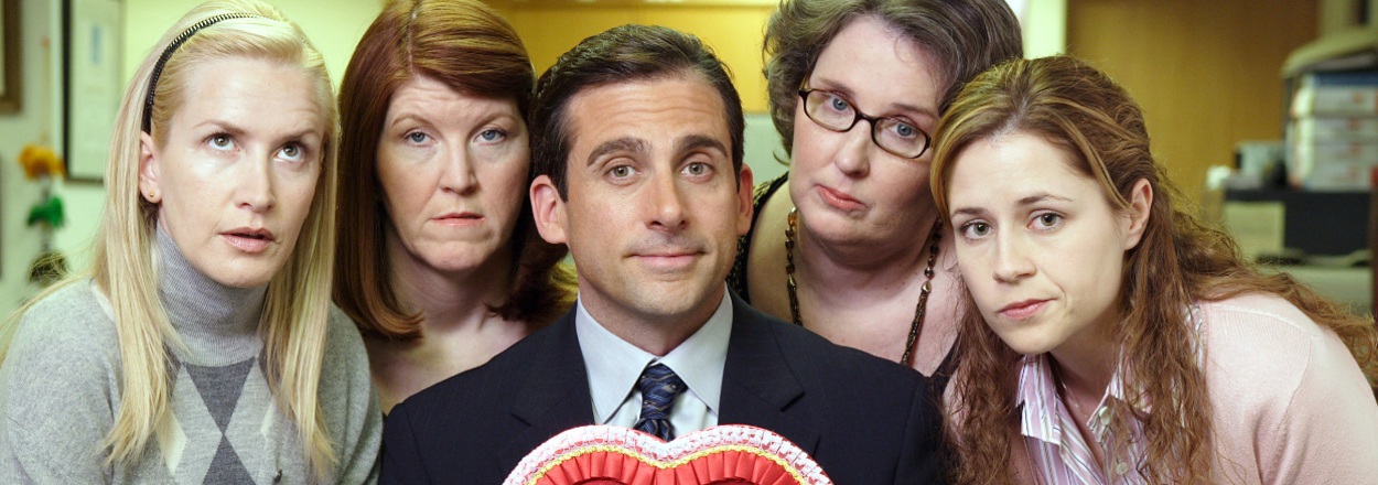 Office TV show characters posing with Michael Scott holding a heart-shaped box
