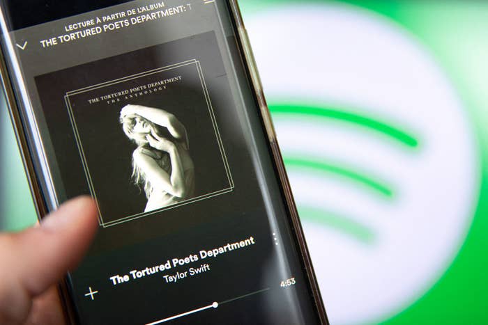 Hand holding a phone with Spotify on screen, displaying Taylor Swift&#x27;s album &#x27;The Tortured Poet&#x27;s Department&#x27;