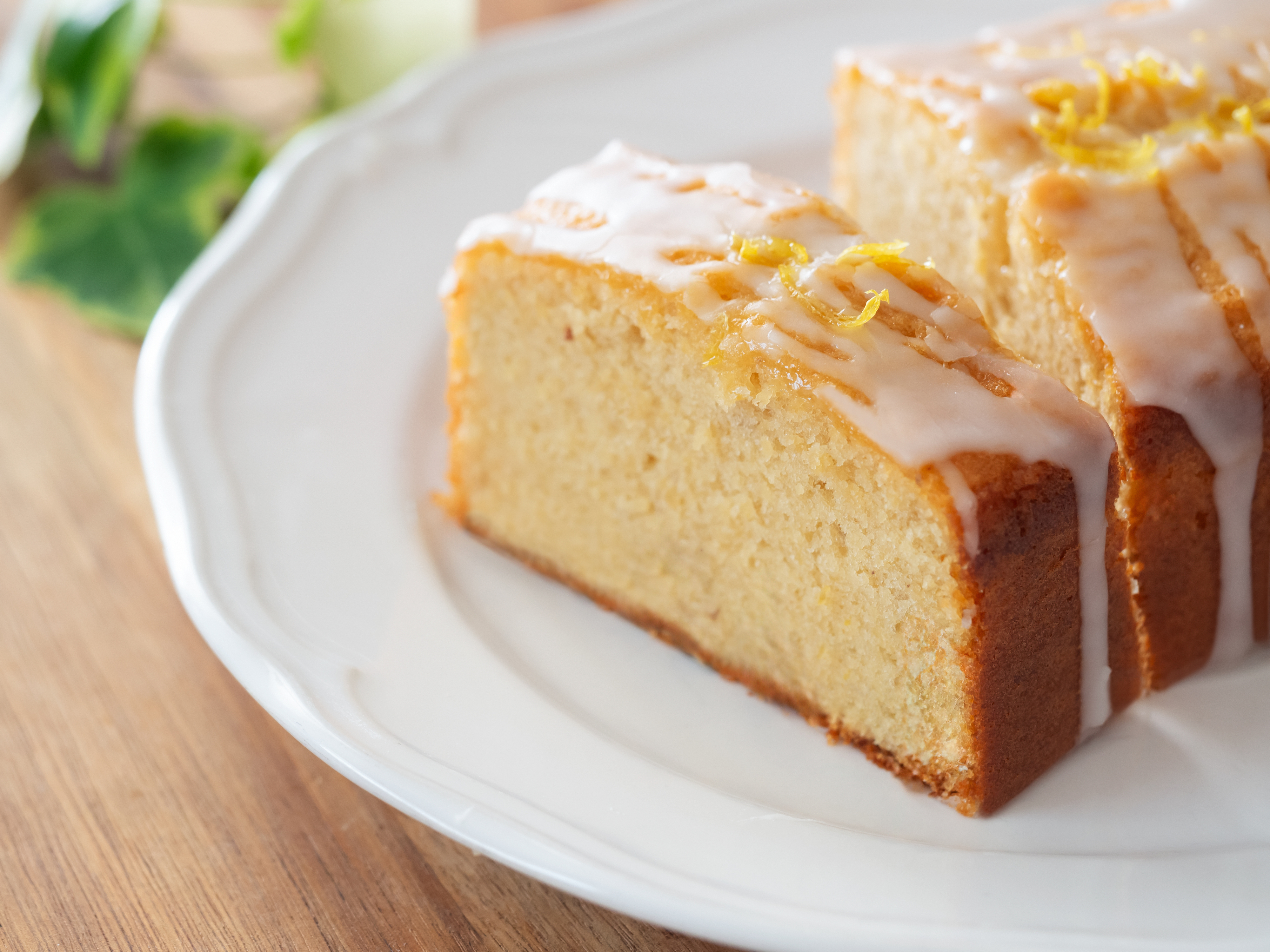 A lemon drizzle cake with icing on top, on a white plate