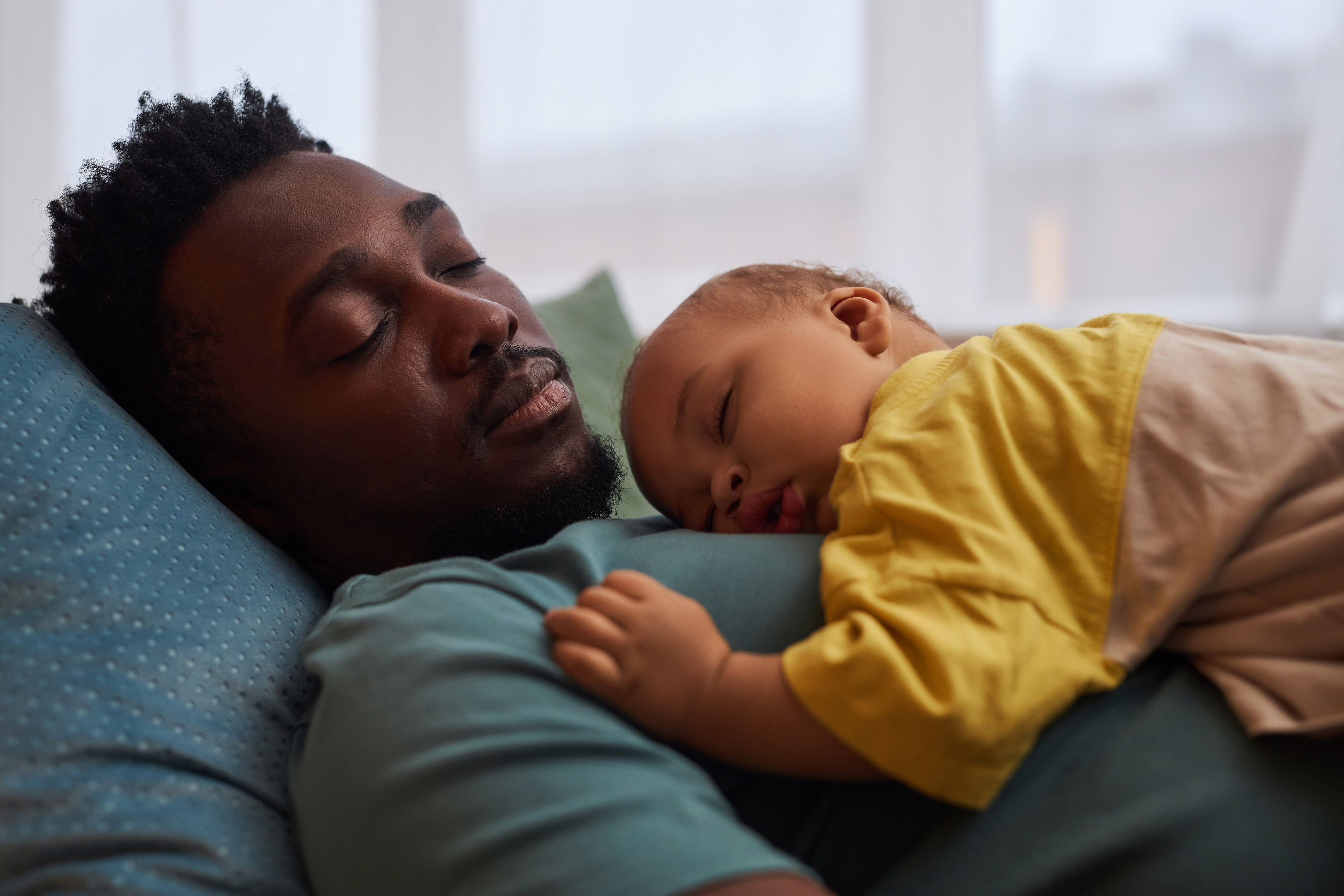 Man reclining with sleeping baby on his chest