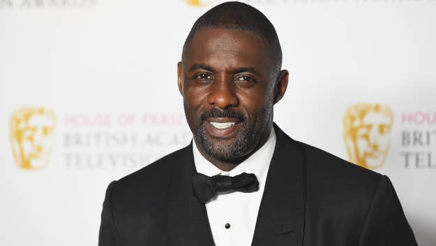 Idris Elba smiling in a black suit and bow tie at a BAFTA event