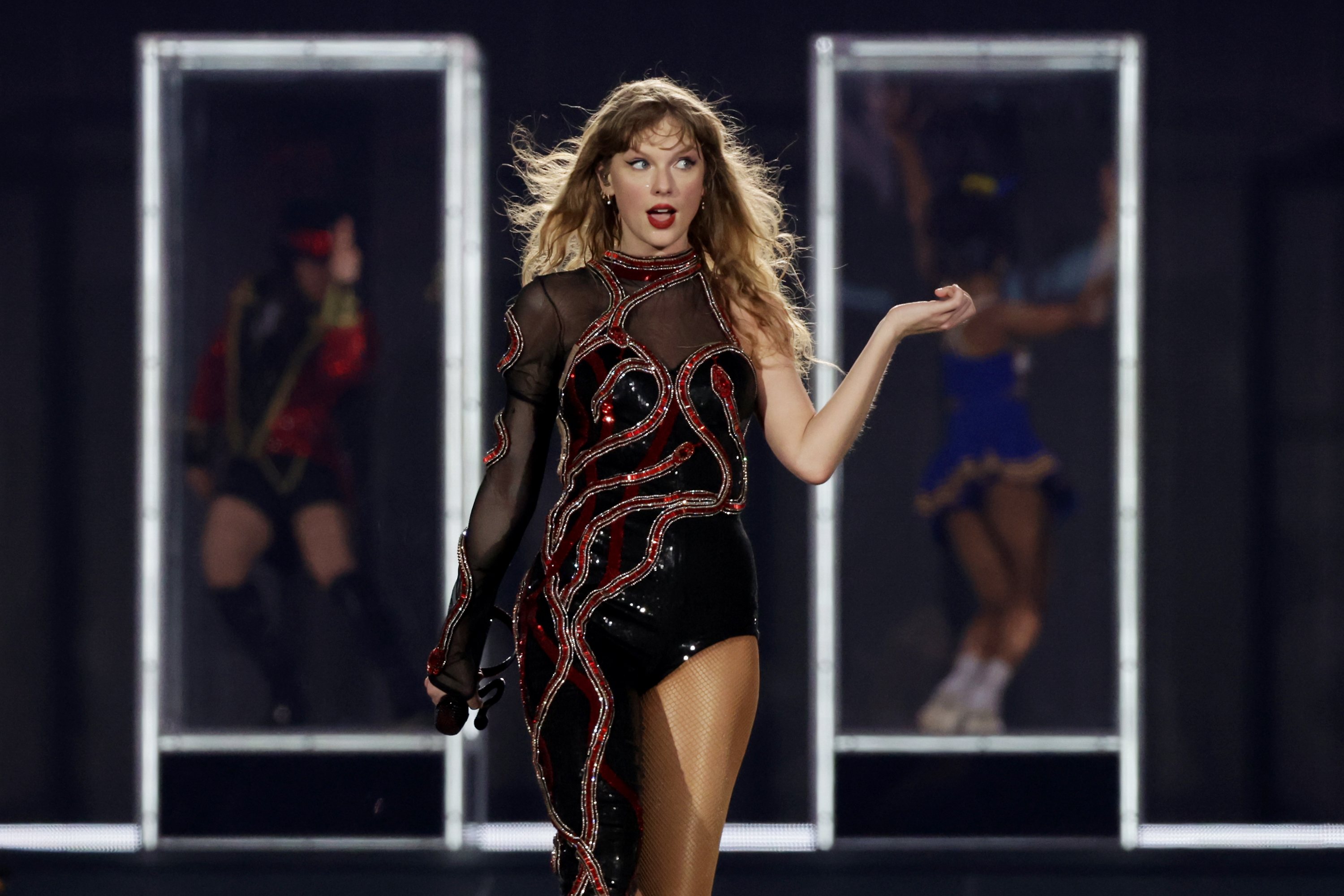 Taylor Swift performing on stage in a sequined outfit with backup dancers in the background