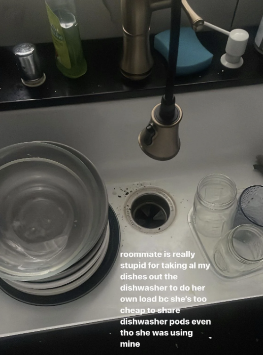 Sink with stacked dishes and glasses beside a handwritten note about a roommate using dishwasher pods