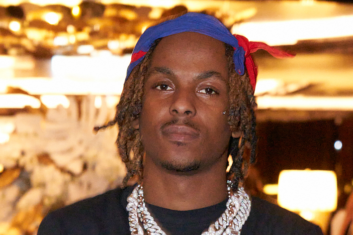 Man with dreadlocks and headscarf, wearing a necklace, looking at the camera