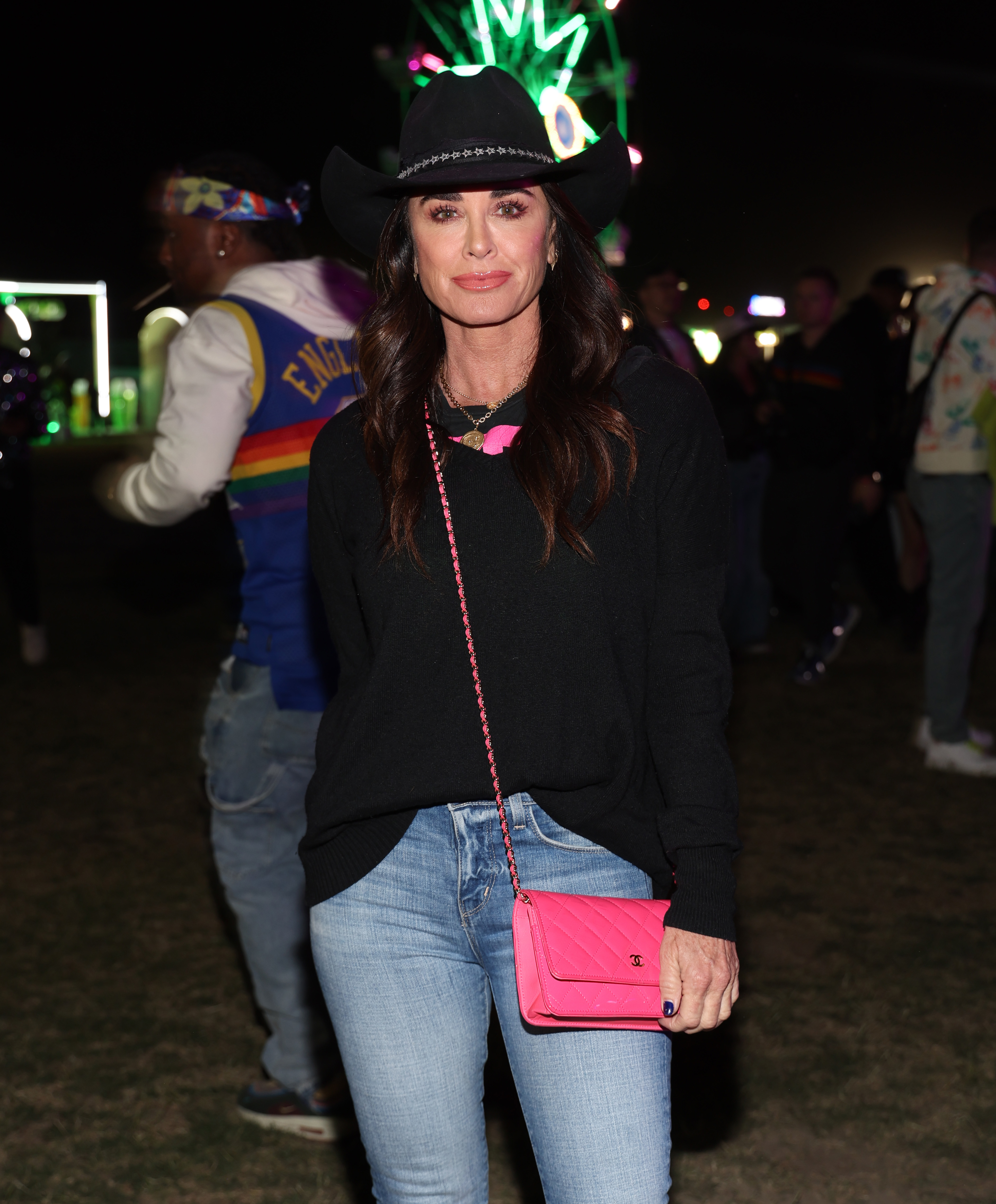Kyle Richards at an event wearing a black top, jeans, and cowboy hat, carrying a pink bag