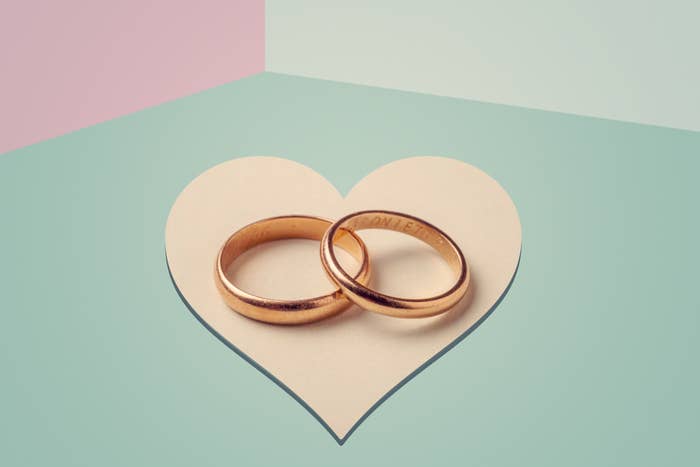 Two wedding bands inside a heart cut-out on a dual-toned background