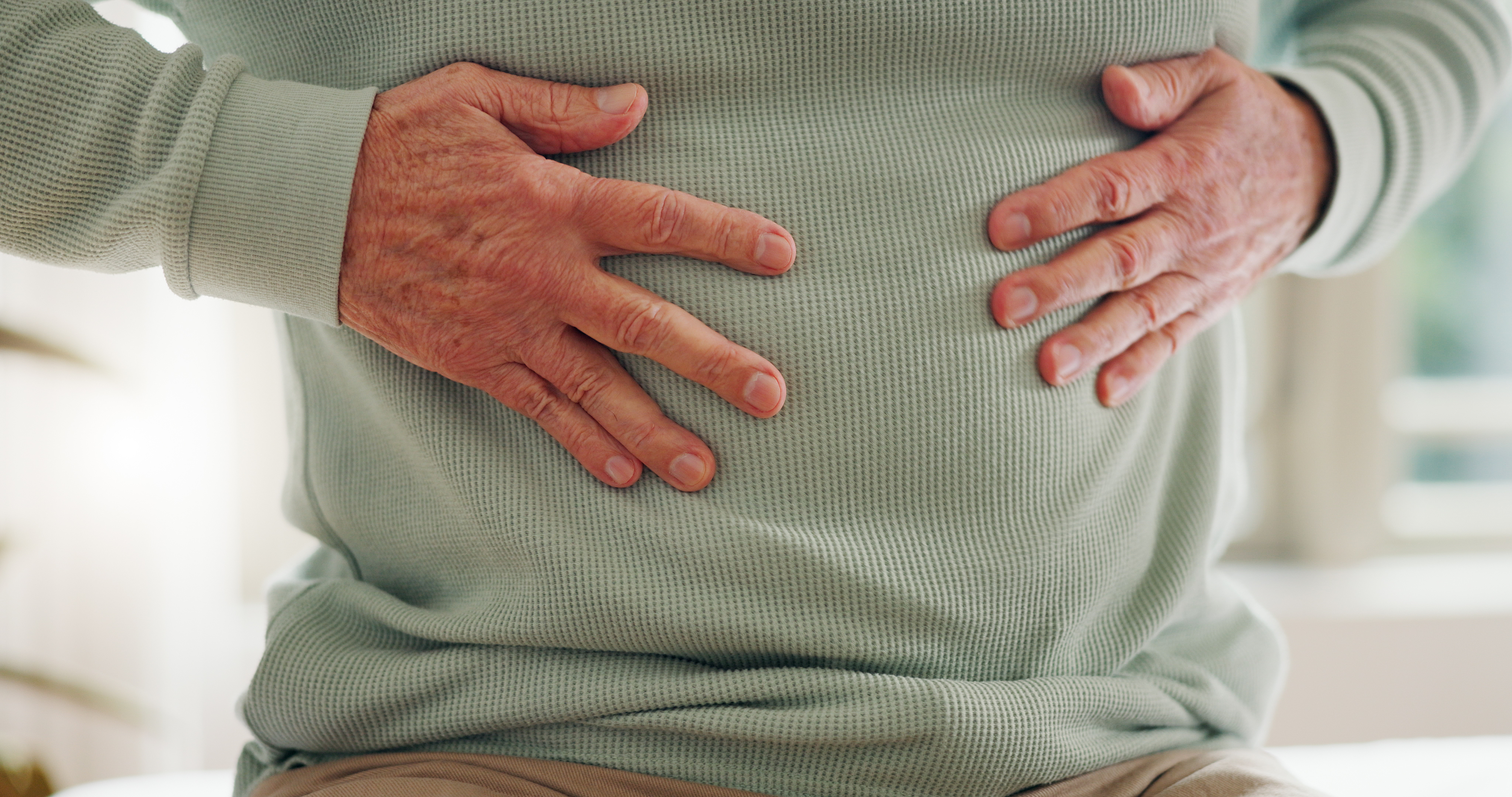 Person clutching their stomach, possibly indicating discomfort or fullness, relevant to a food-related context