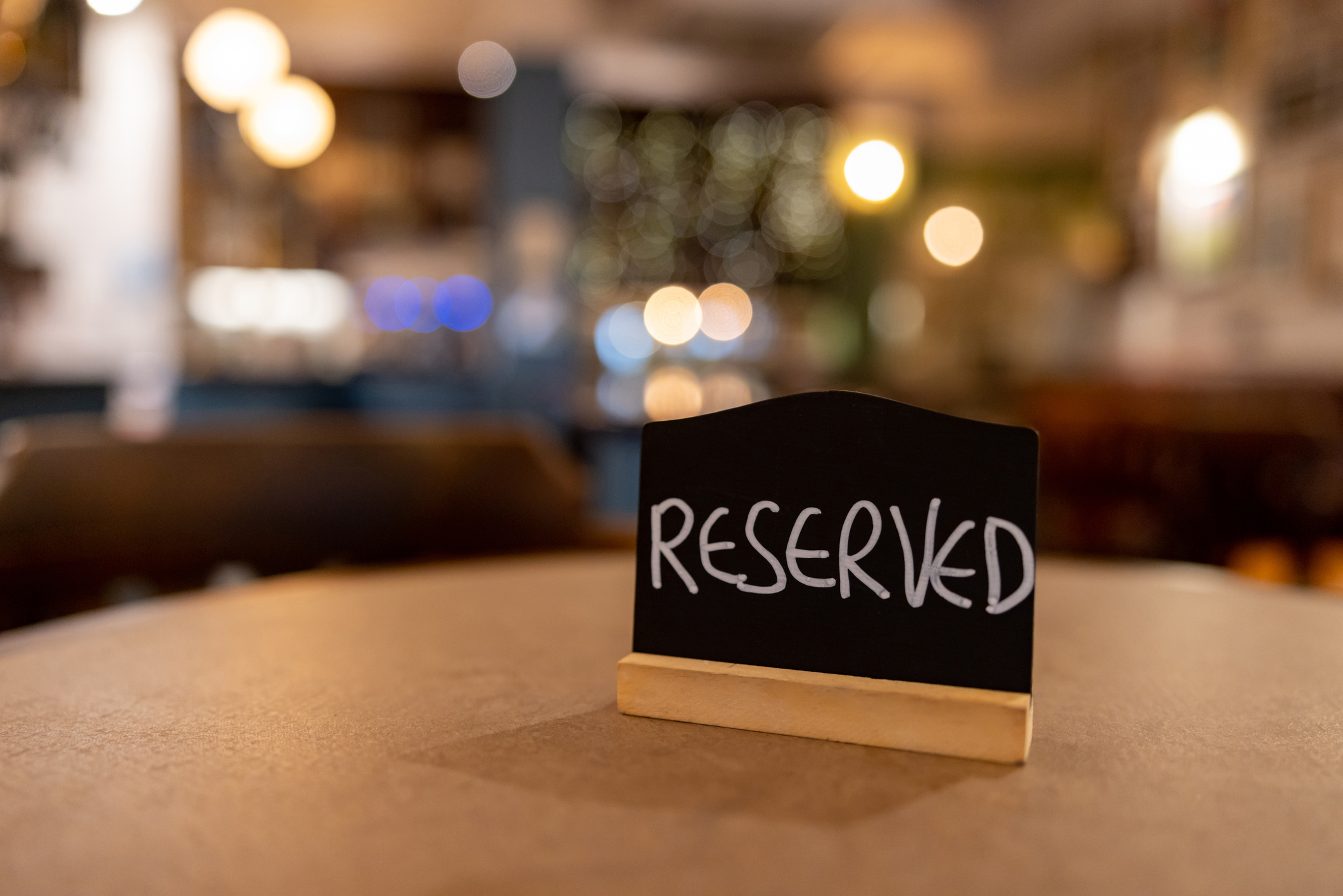 Reserved sign on a table in a softly lit restaurant ambiance