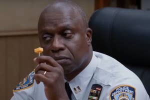 Captain Holt from Brooklyn Nine Nine holding a cheese snack, looking pensive
