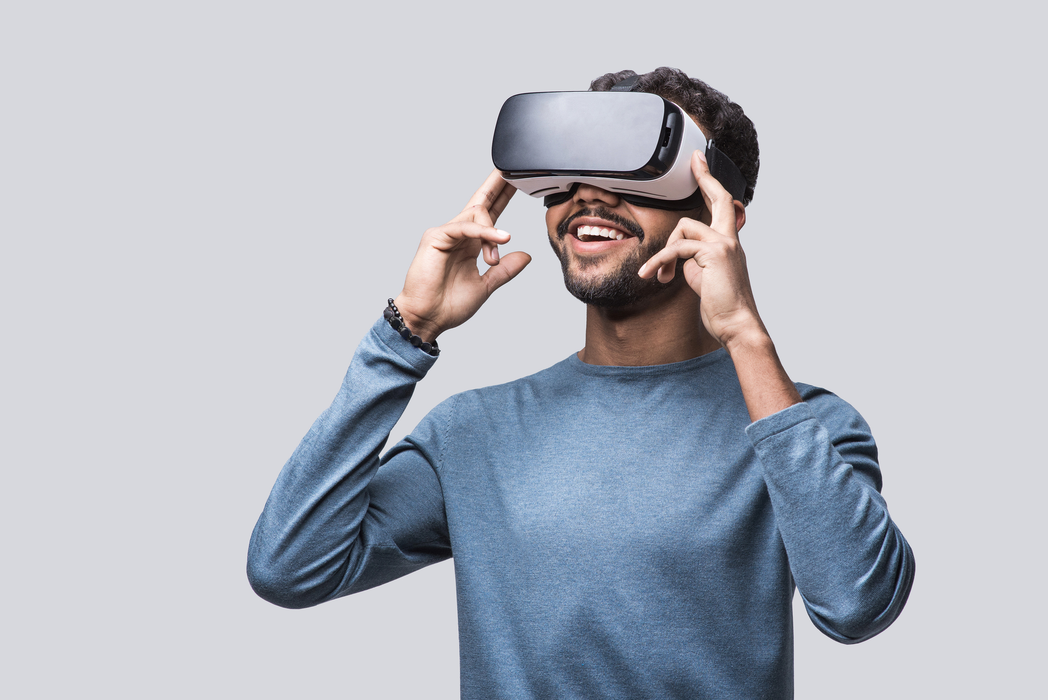 Man wearing a virtual reality headset, appears engaged and smiling, touching the headset