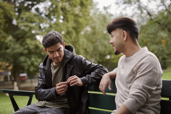 Two men in casual attire chatting on a park bench