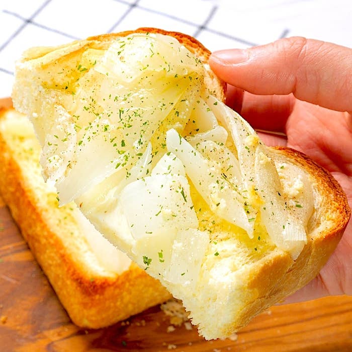 手に持っているトーストに玉ねぎがトッピングされています。